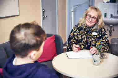 Skolsköterska samtalar med en elev vid ett bord. Solhemsskolan i Spånga