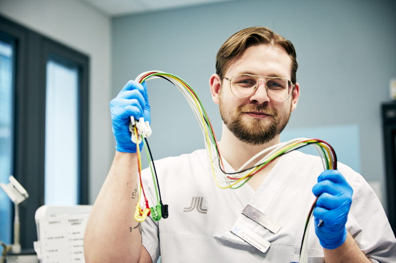 Biomedicinsk analytiker, klinisk fysiologi, arbets-EKG, leende man håller i elektroder, Karolinska sjukhuset i Solna
