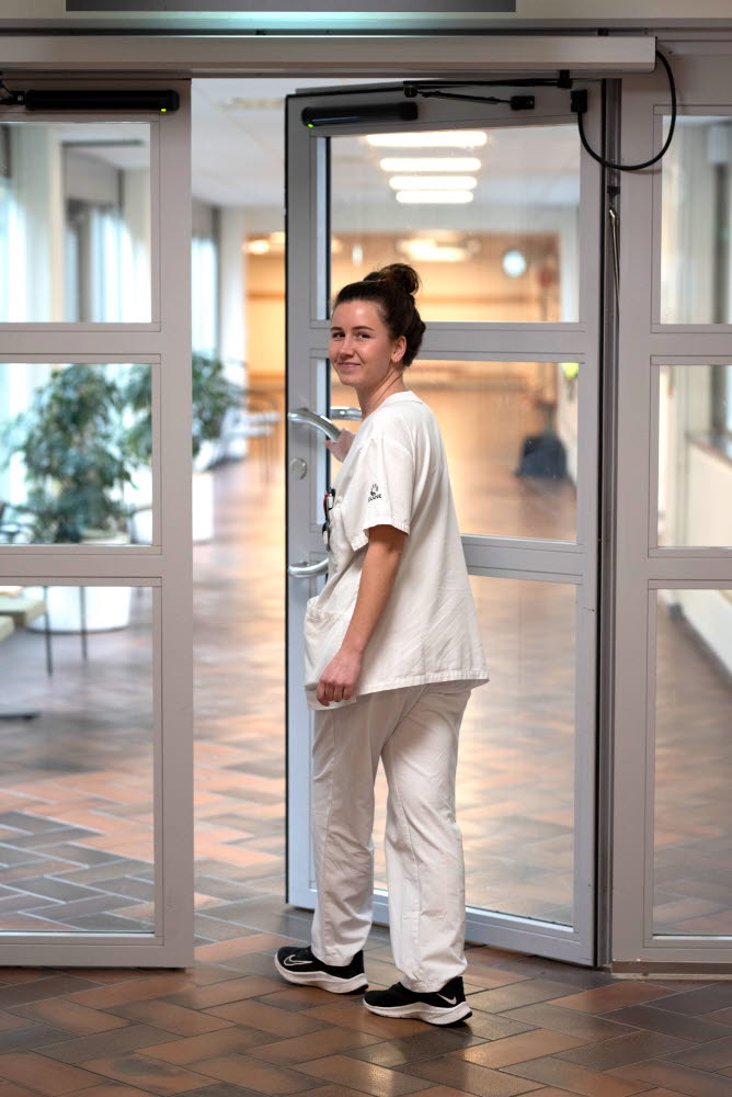 Lina Nilsson, sjuksköterska, tittar bakåt och går ut genom en dörr, Centralsjukhuset Kristianstad. Årsberättelse 2021.