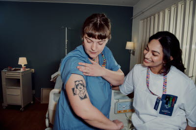 Sjuksköterska visar upp sin tatuering för en kollega.