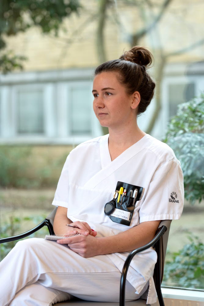 Lina Nilsson, sjuksköterska, sitter och funderar med ett block i knät, Centralsjukhuset Kristianstad. Årsberättelse 2021.