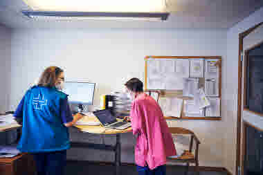 Sjuksköterska och läkare planerar vid ett skrivbord, äldreboende. 