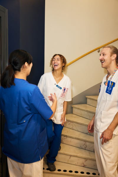 Man och kvinna. Sjuksköterskor träffar en röntgensjuksköterska i ett trapphus. 