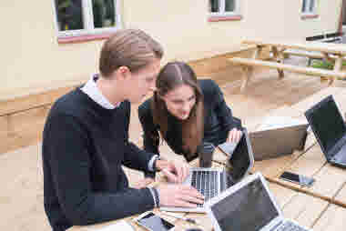 Studenter under grupparbete. Man och kvinna med laptops, pc.