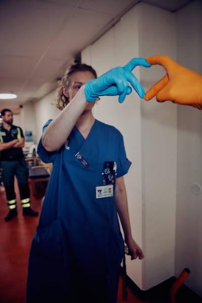 Två olikfärgade handskbeklädda händer formar ett hjärta.