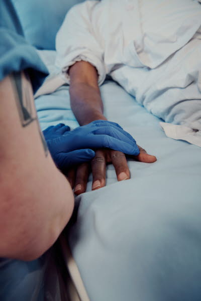 Omtanke, medmänsklighet. Sköterska med blå plasthandske har lagt sin hand över patientens.
EJ ANVÄNDA - ej korrekt att ha handske på när du visar omtanke