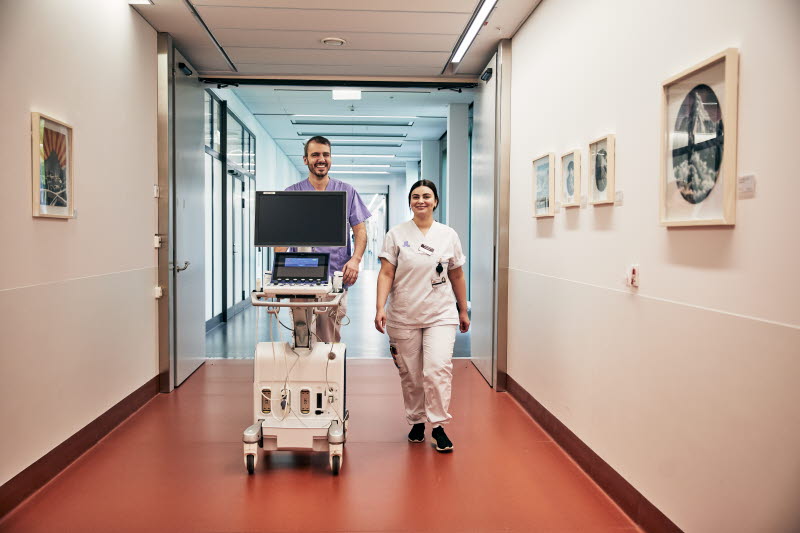 Biomedicinsk analytiker, klinisk fysiologi, ultraljud på hjärtat, man och kvinna går i korridor med teknisk utrustning, Karolinska sjukhuset i Solna