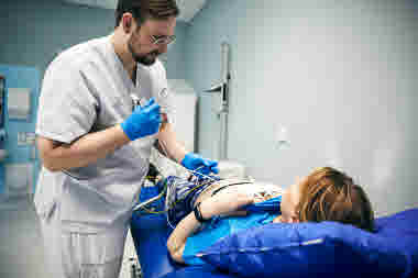 Biomedicinsk analytiker fäster elektroder på patient som ligger på brits, klinisk fysiologi, arbets-EKG, man, Karolinska sjukhuset i Solna