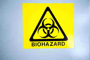 Varningsskylt Biohazard. Varningsskylten är gul med svart symbol och text.