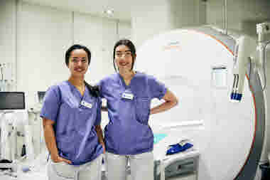 Biomedicinsk analytiker, klinisk fysiologi, två glada kvinnor framför MR-röntgen, Karolinska sjukhuset i Solna