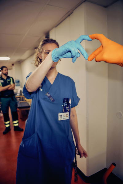 Två olikfärgade handskbeklädda händer formar ett hjärta.