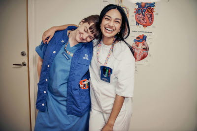 Två glada kvinnliga kollegor som håller om varandra. En axel att vila på. Omtanke, glädje, gemenskap.