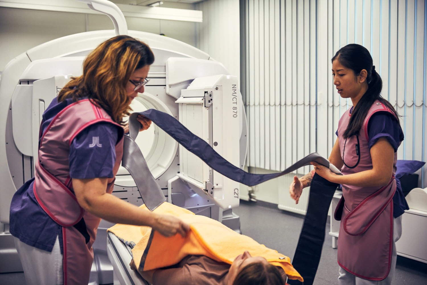 Två röntgensjuksköterskor som förbereder en patient. Danderyds sjukhus, röntgen, nuklearmedicin. Oktober 2021.