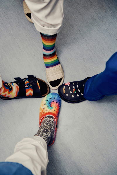Fyra fötter i färgglada strumpor och olika typer av tofflor. Personlighet, olikhet, gemenskap. 