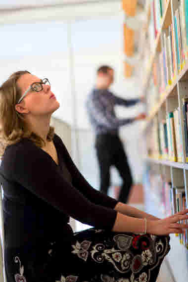 Student letar bok bland hyllorna på ett bibliotek.