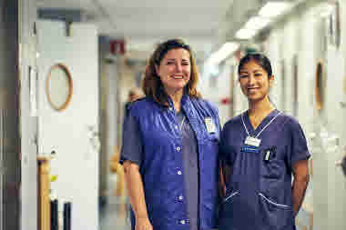 Två glada röntgensjuksköterskor i en korridor. Danderyds sjukhus, röntgen, nuklearmedicin. Oktober 2021.
