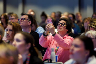 Vårdförbundets kongress 2026. Mötesdeltagare i stormöte. En deltagare håller upp en telefon och filmar.