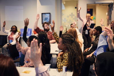 Årsmöte student 2025. Mötesdeltagarna räcker upp händerna. Röstning