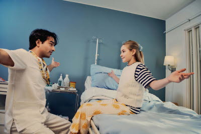 Sjuksköterska tillsammans med en flicka som  utför armrörelser.