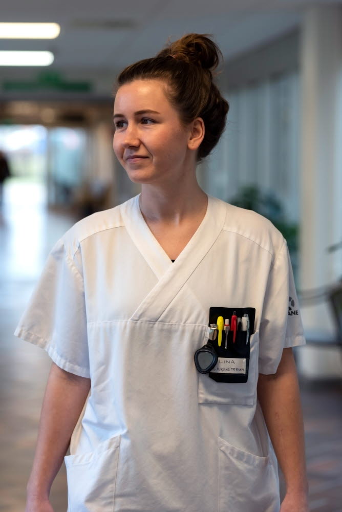 Lina Nilsson, sjuksköterska, gående i en korridor, tittar åt sidan, Centralsjukhuset Kristianstad. Årsberättelse 2021.