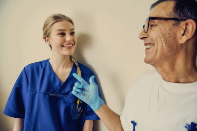 Samtal mellan kollegor. Glädje, gemenskap. Hand med handske med texten Du är bäst! som pekar på kollegan.