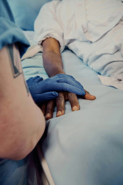 Omtanke, medmänsklighet. Sköterska med blå plasthandske har lagt sin hand över patientens.

EJ ANVÄNDA - ej korrekt att ha handske på när du visar omtanke