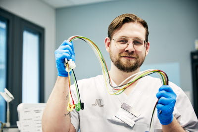 Biomedicinsk analytiker, klinisk fysiologi, arbets-EKG, leende man håller i elektroder, Karolinska sjukhuset i Solna