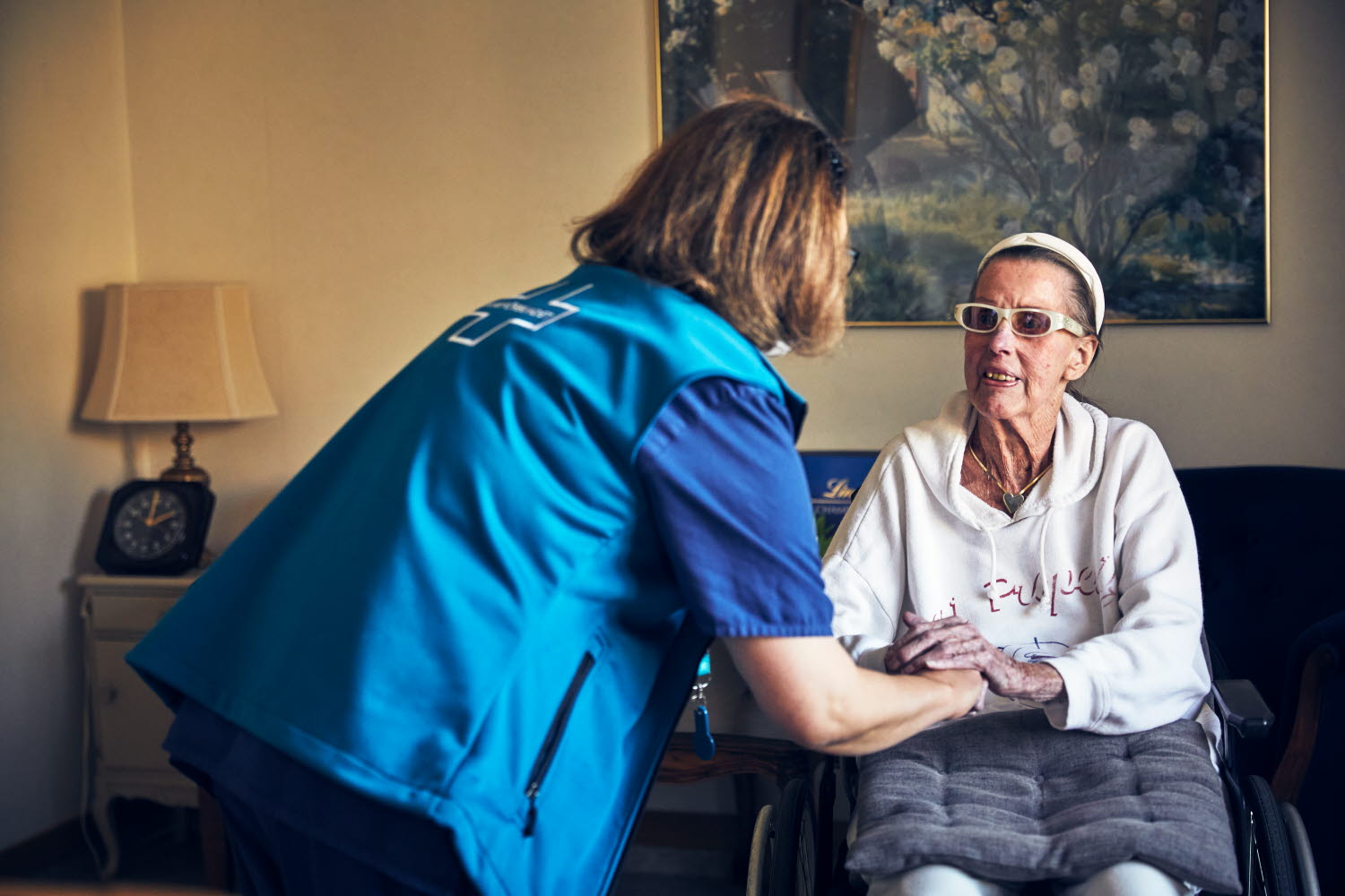 Sjuksköterska samtalar och håller en boende i handen. Omvårdnad. RIO äldreboende.